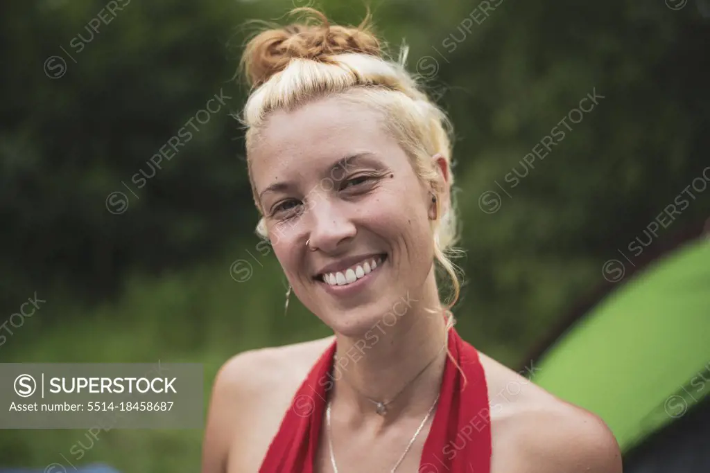 beautiful blonde woman in red smiles outside camps in forrest