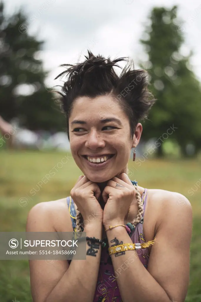 non-binary asian smiles in colourful croptop at festival camp