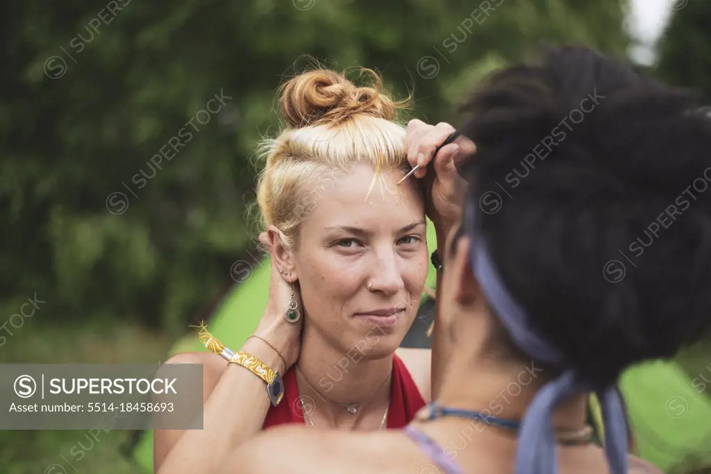 beautiful woman smiles at festival getting her face painted gold