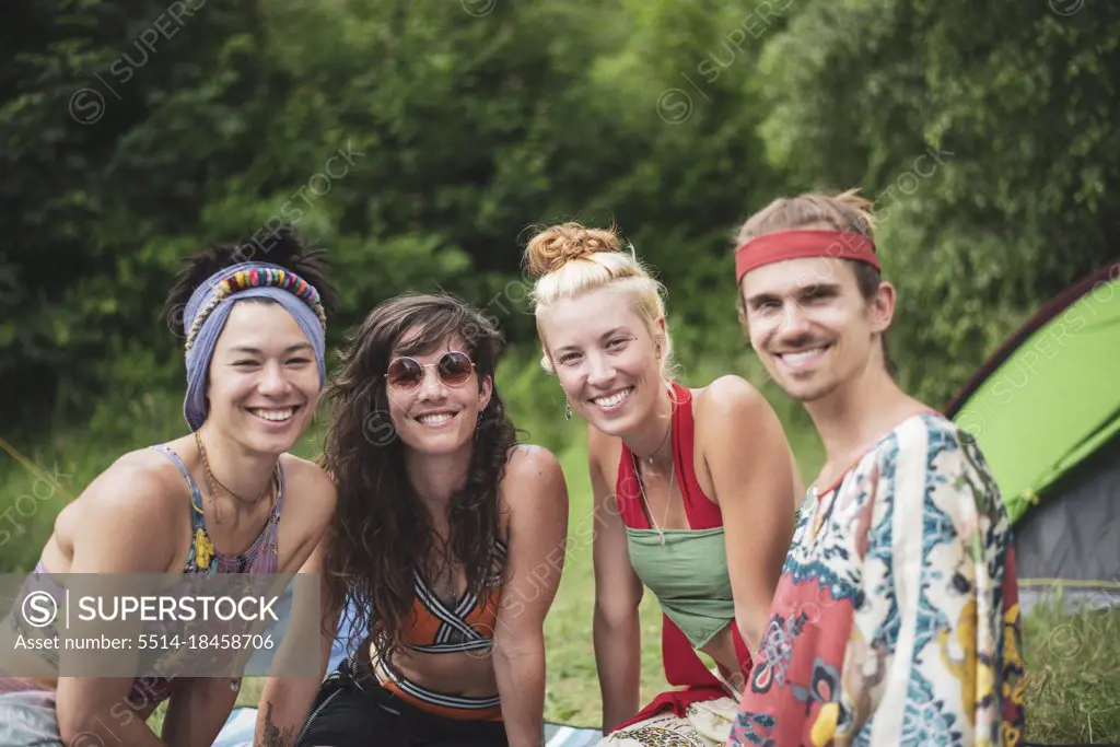 Colourful group of queer friends smile at festival camp in nature