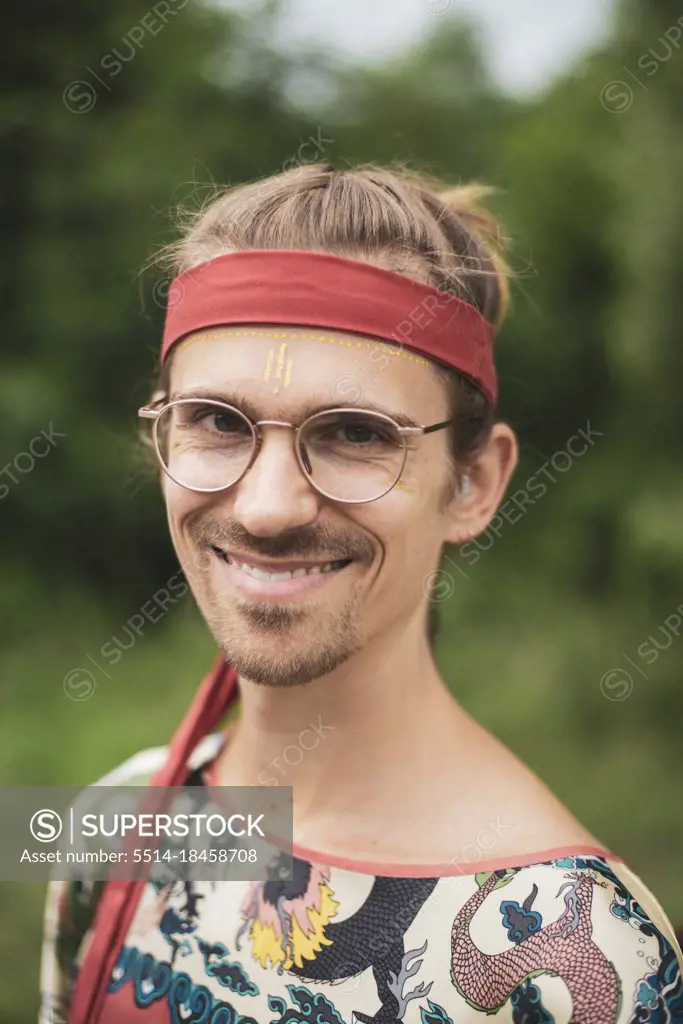 happy man at festival with glasses, facepaint and red bandana
