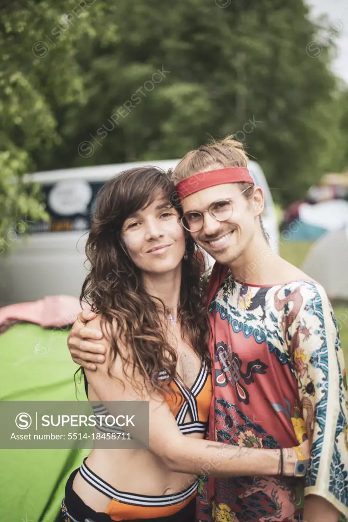 Two bohemian friends hugging smiling wearing funky clothes at festival