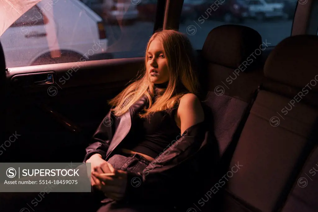 Blonde woman sitting in a car salon in the evening