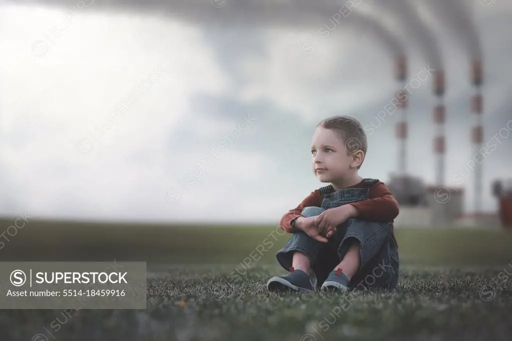 Little boy sitting on the grass environmental pollution concept.