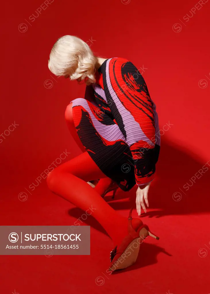 female fashion model in red dress posing isolated on red background