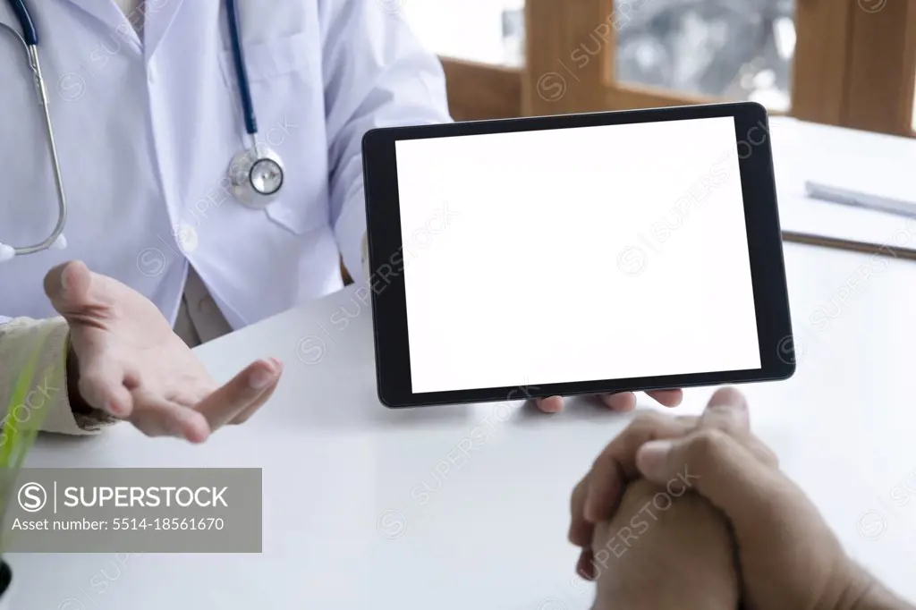 Doctor using computer tablet discussion something with patient.