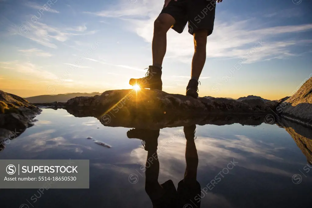 Lower half view of hiker wearing boots on mountain summit