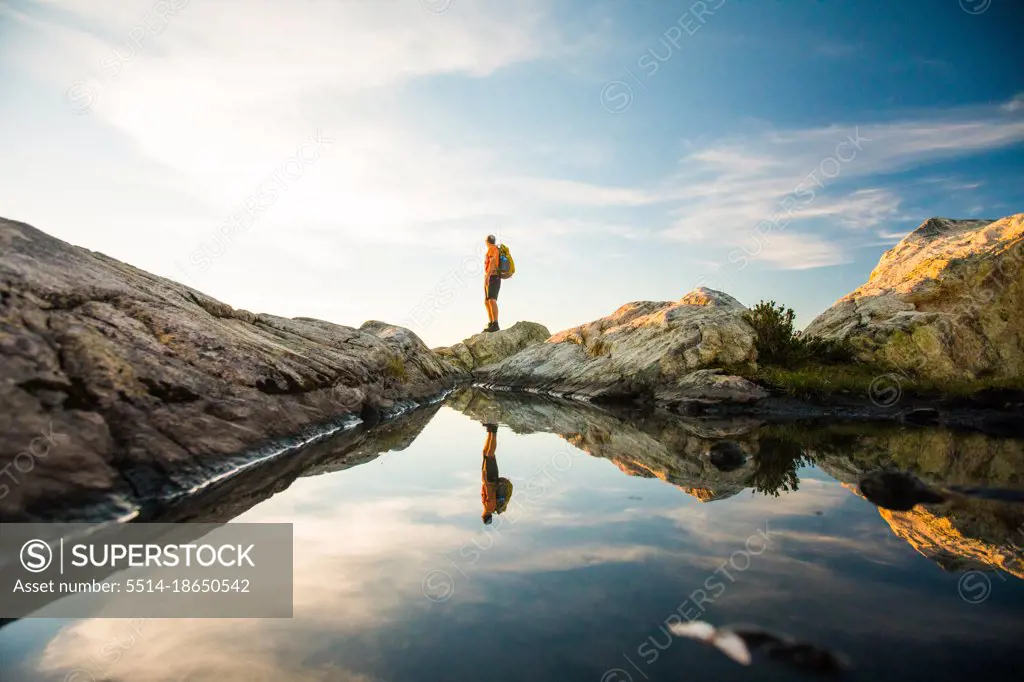 reflection of hiker standing on mounatin summit.