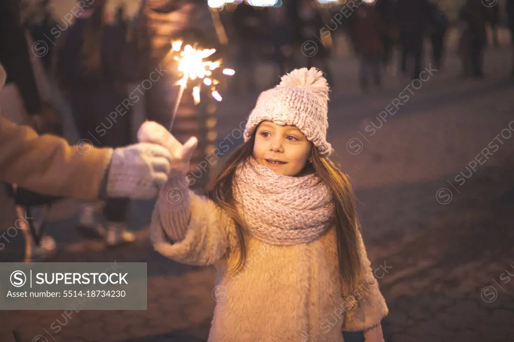 Little girl decorated of ligh and holds burning sparkles
