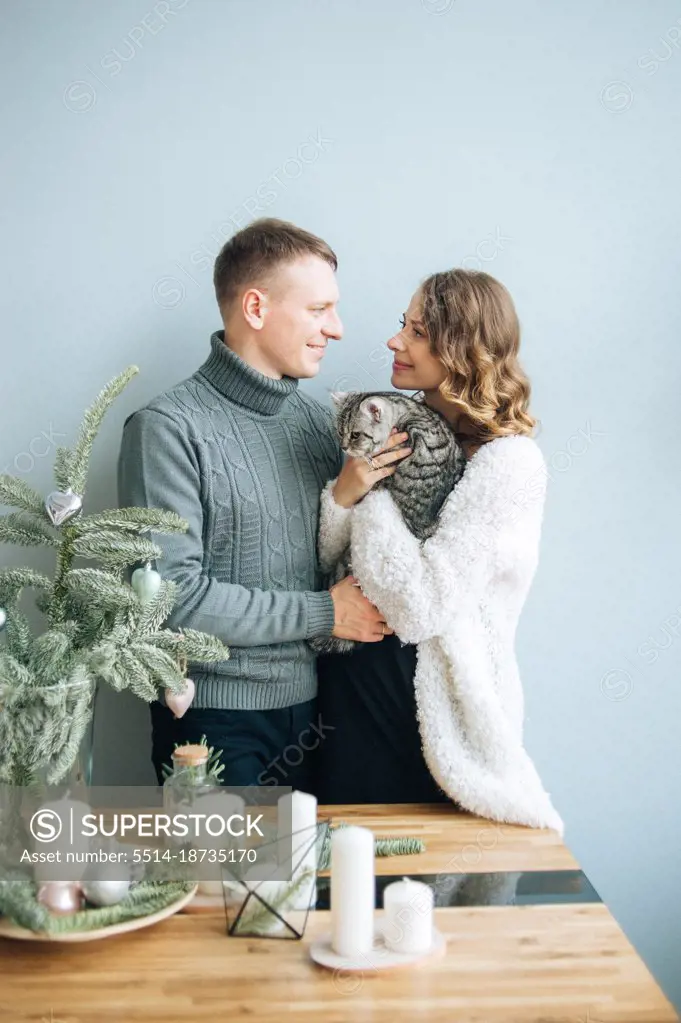 Woman and man look tender into eyes each other.Pregnant woman hold cat