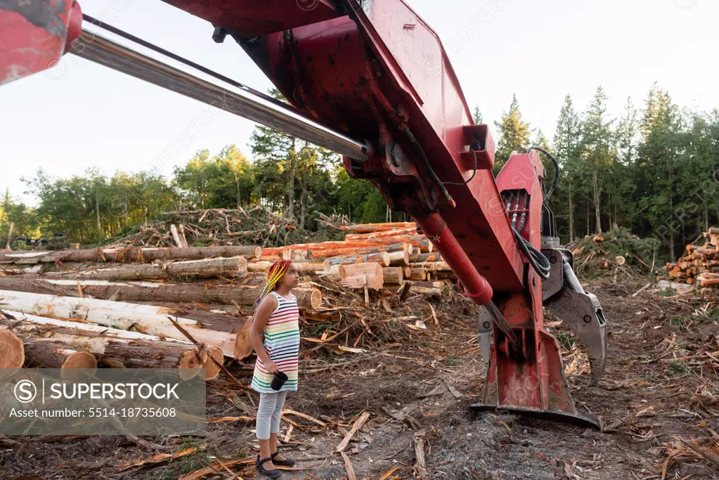 Girl stands under logging loader