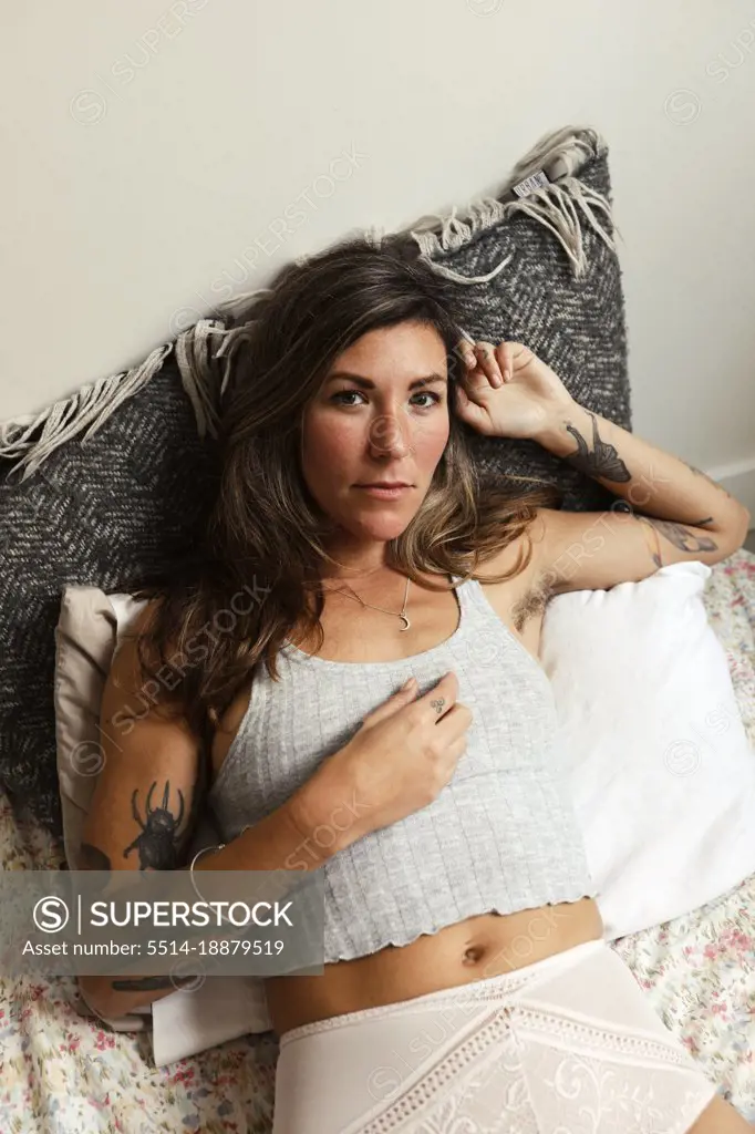 Beautiful woman with tattoos lounges in bed