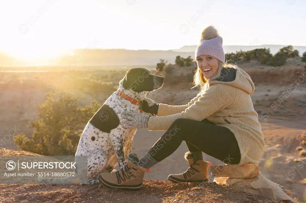 Portrait of happy woman with dog sitting in desert