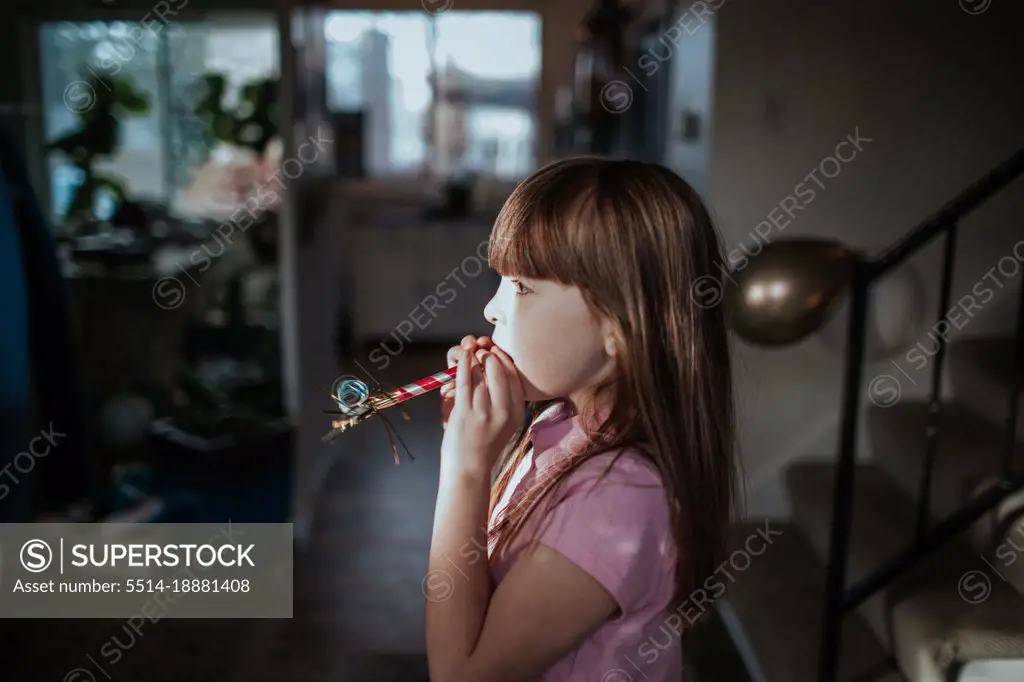 Young girl standing with party favor in mouth