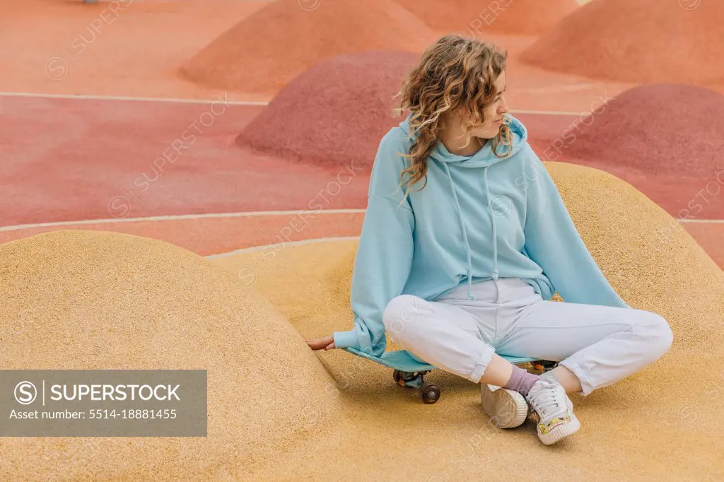 Teenager on skateboard relaxing sitting in skate park.