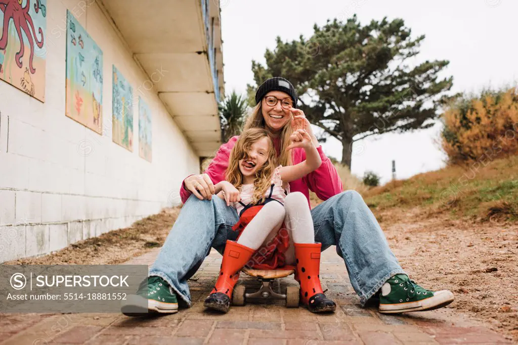 mother and daughter on a skateboard laughing having fun