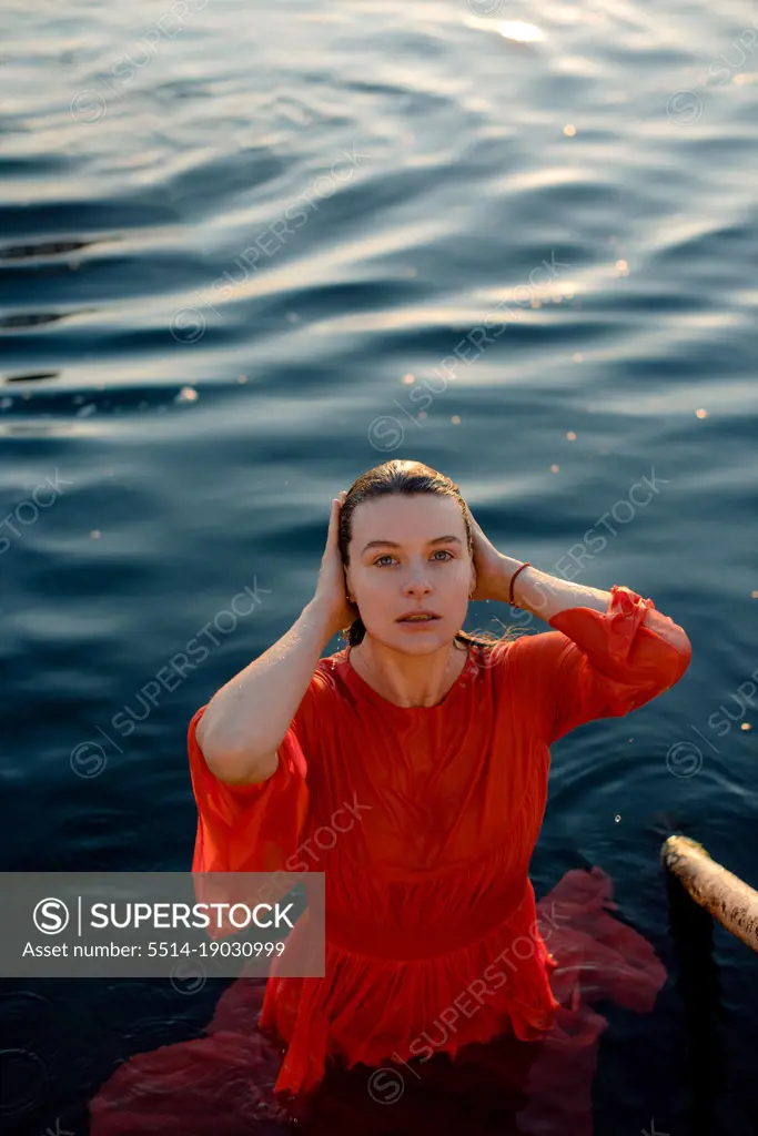 portrait of a woman in a wet red dress in blue water