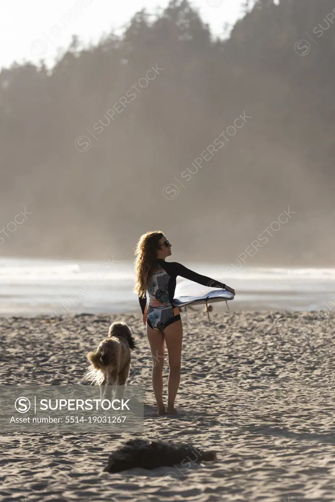 Woman carrying surboard down the beach along the Oregon coast