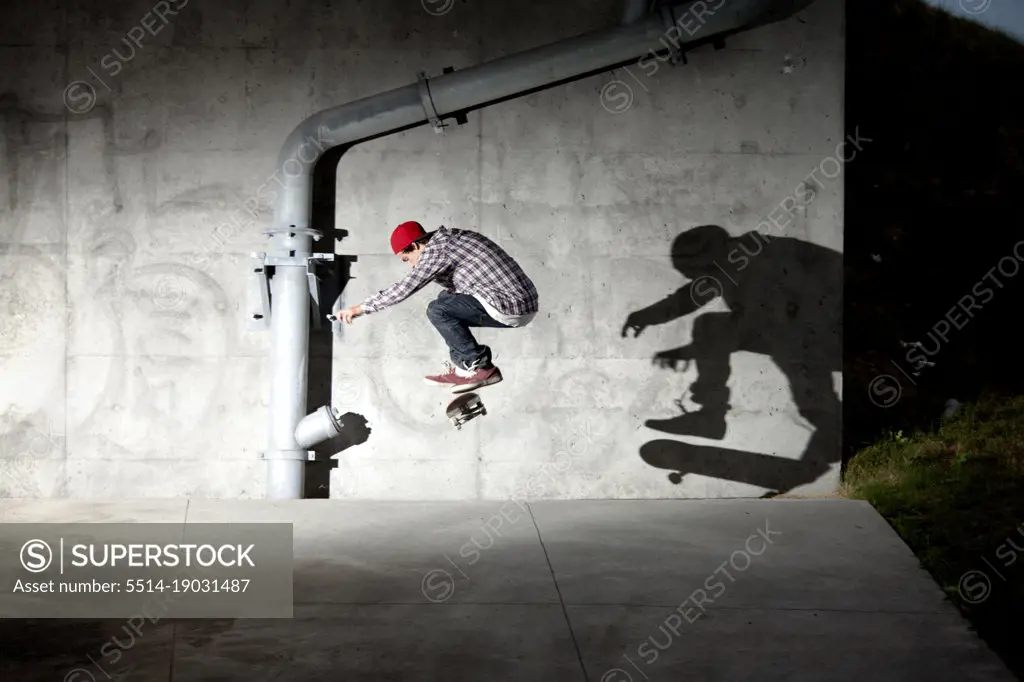 Skateboarder skating under overpass at night