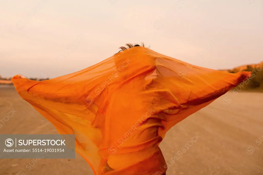 woman with orange cloth in desert with wind