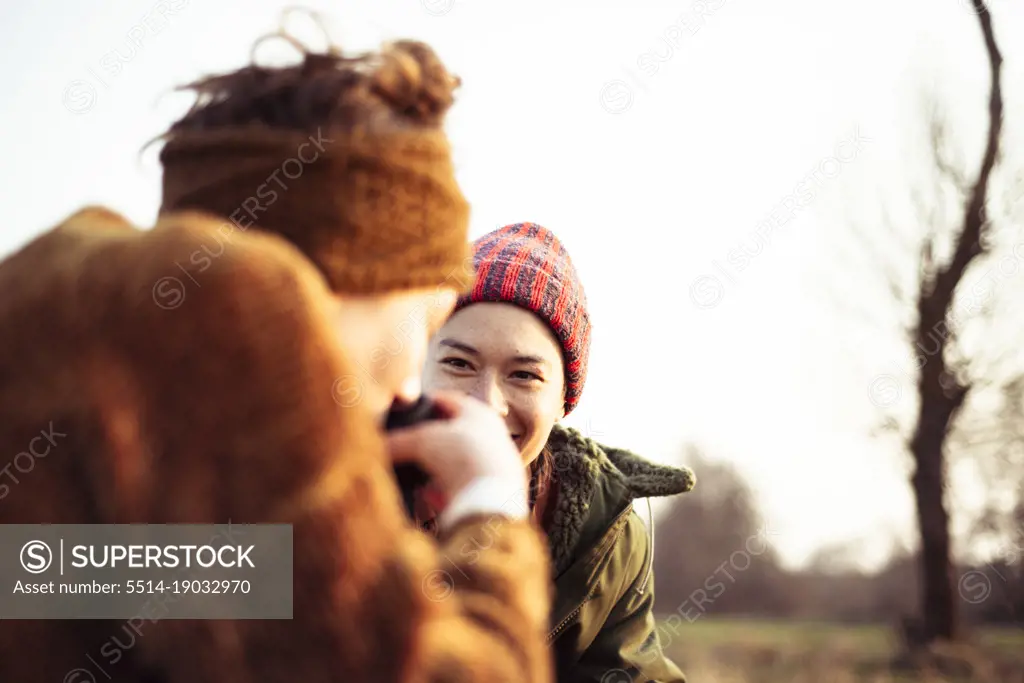 friends laugh and drink tea in winter sun picnic in the field