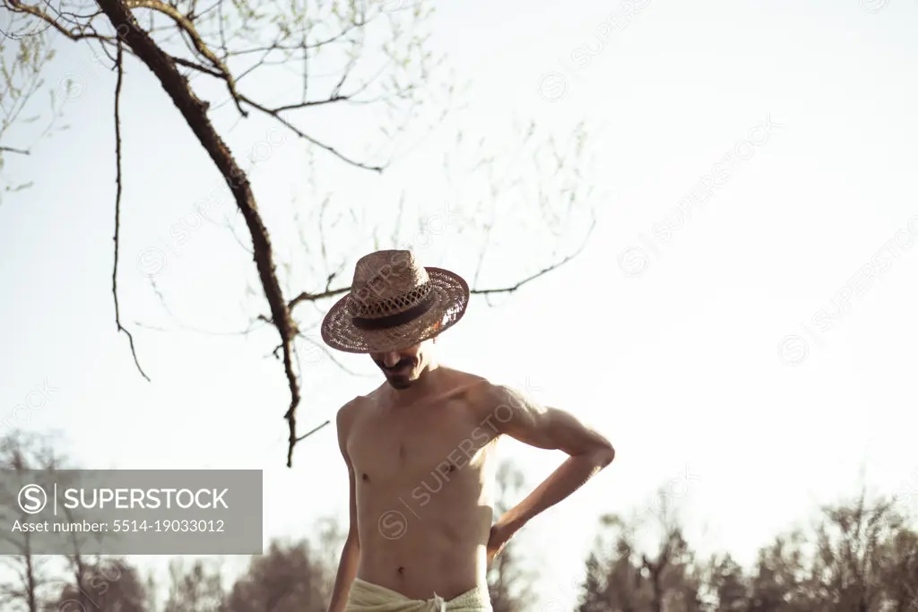 Healthy muscular lean young man wearing hat in nature