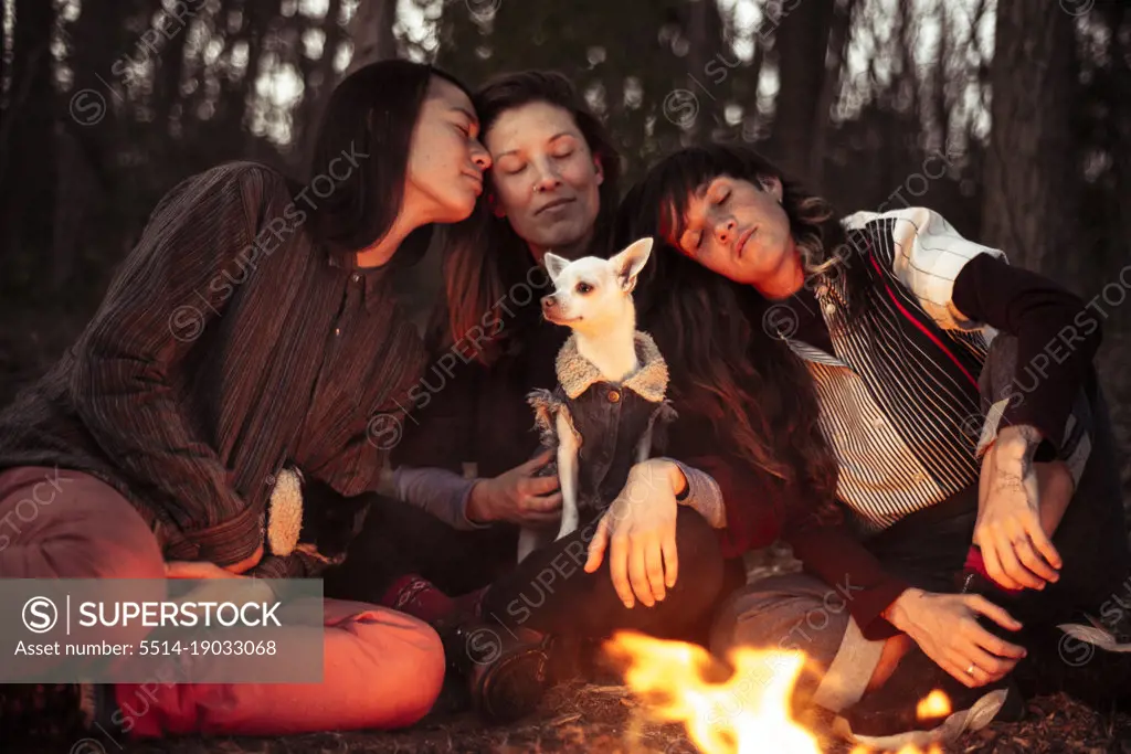 intimate women friends with small dog cosy by fireside
