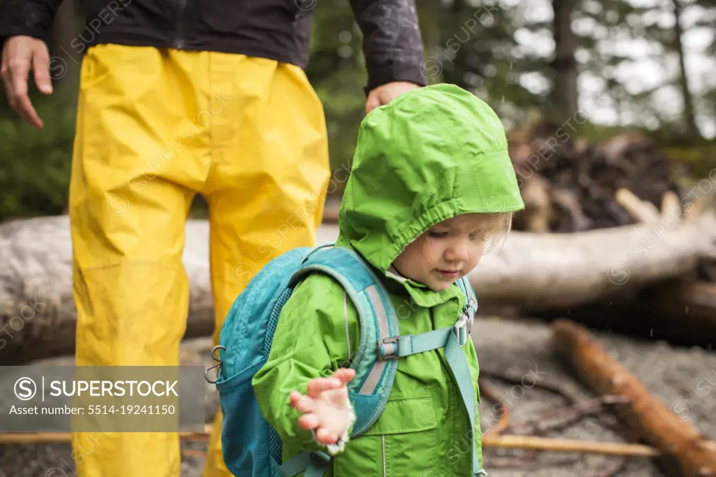 Young child in rain coat on rocky beach
