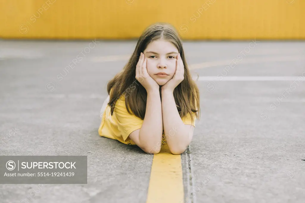 Young girl lying on the ground resting her head in her hands