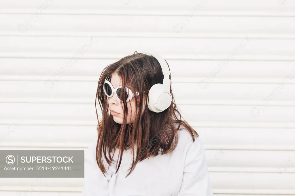 Girl standing outside wearing sunglasses and headphones