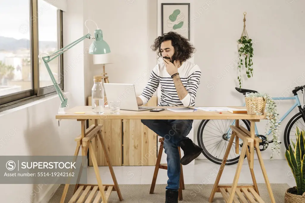 Man sitting and working in his wooden studio using his laptop