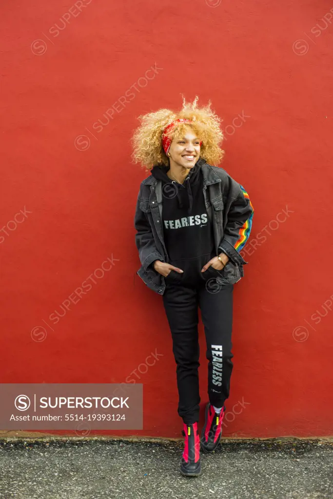 crazy Blond haired woman standing against re wall