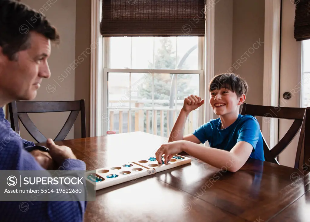 Boy and his father having fun playing a game together at home.