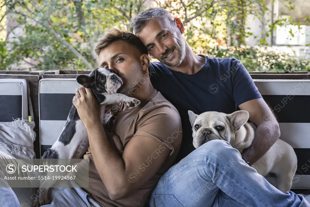 Portrait of a gay male couple and their french bulldogs.