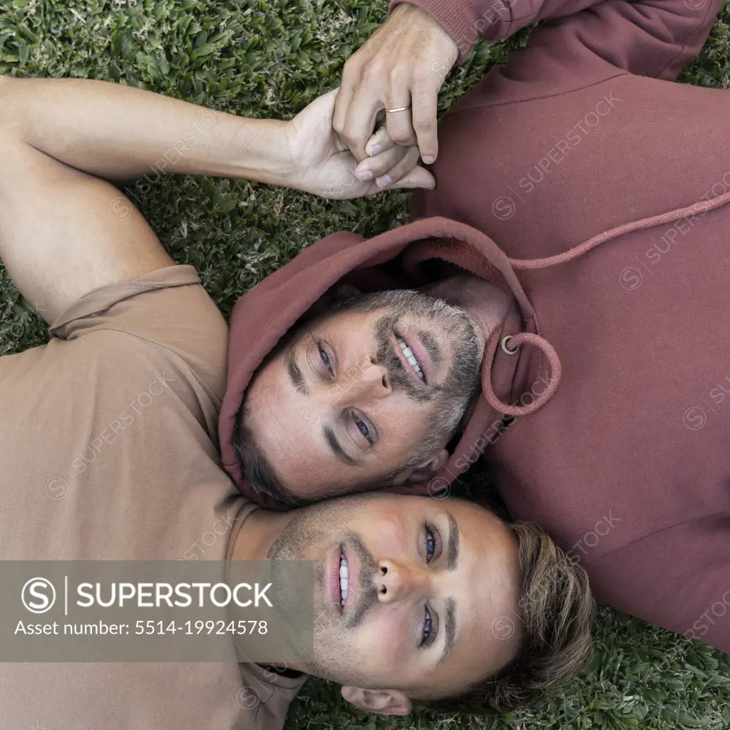 Top view of a male gay couple lying on the grass