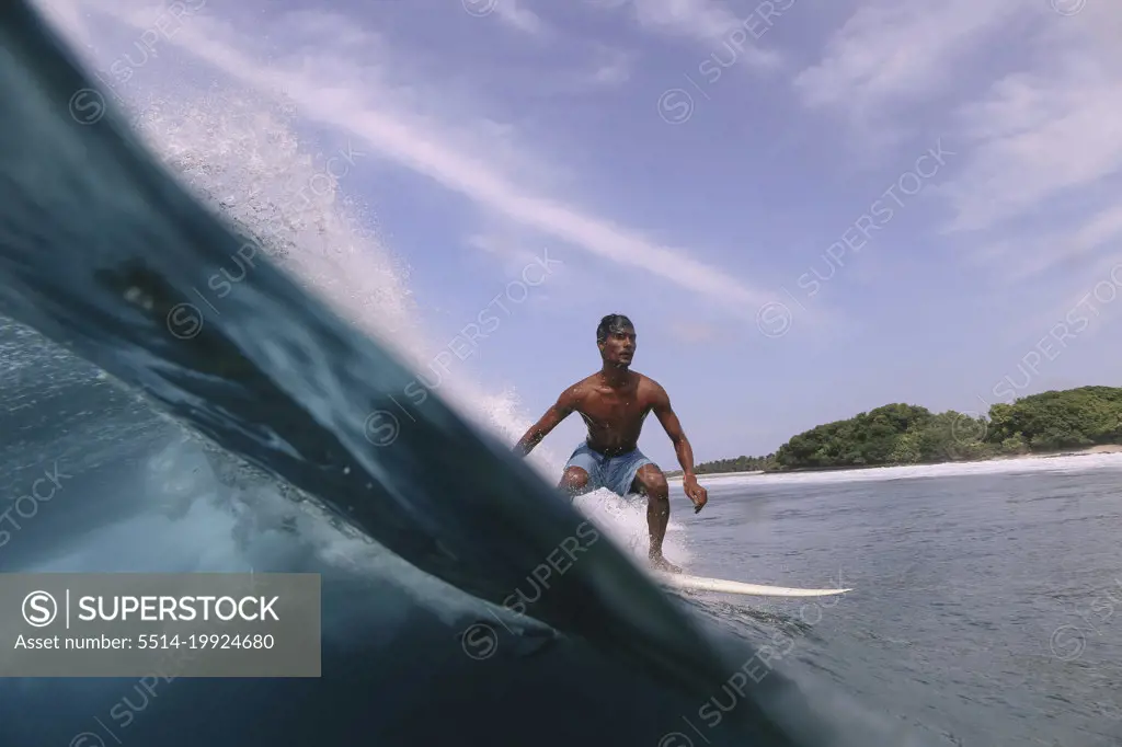 Asian surfer on a wave at sunny day
