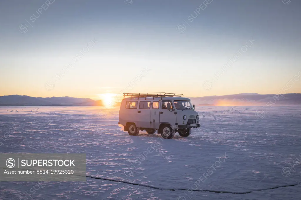 old van over frozen lake at sunset