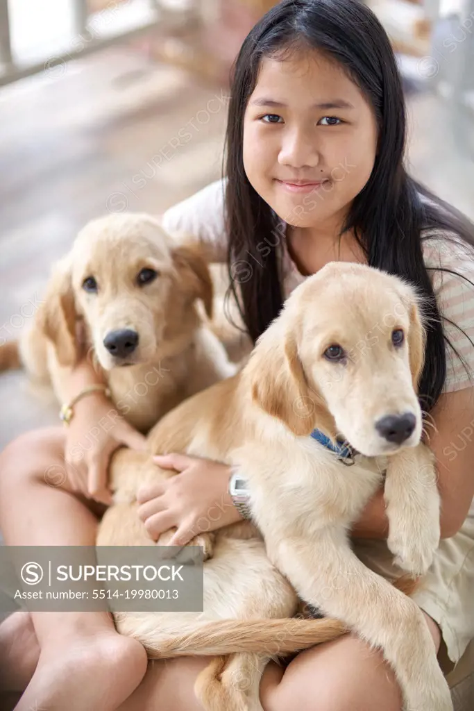 Portrait of a girl with a golden retriever puppy in her embrace