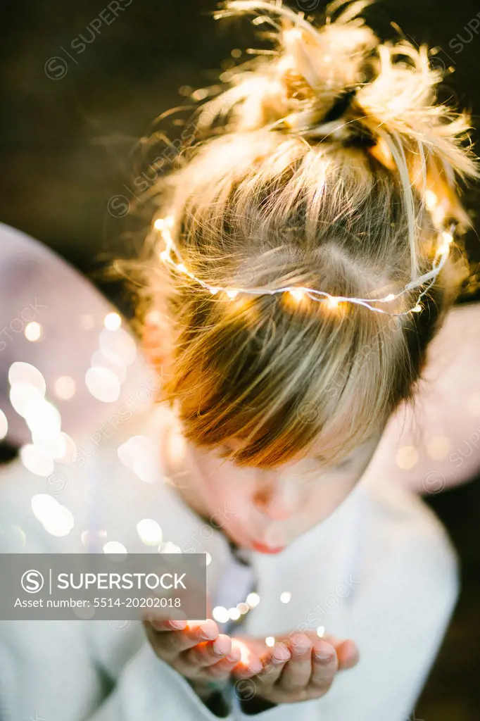 Blond girl child in angel wings with fairy dust lights