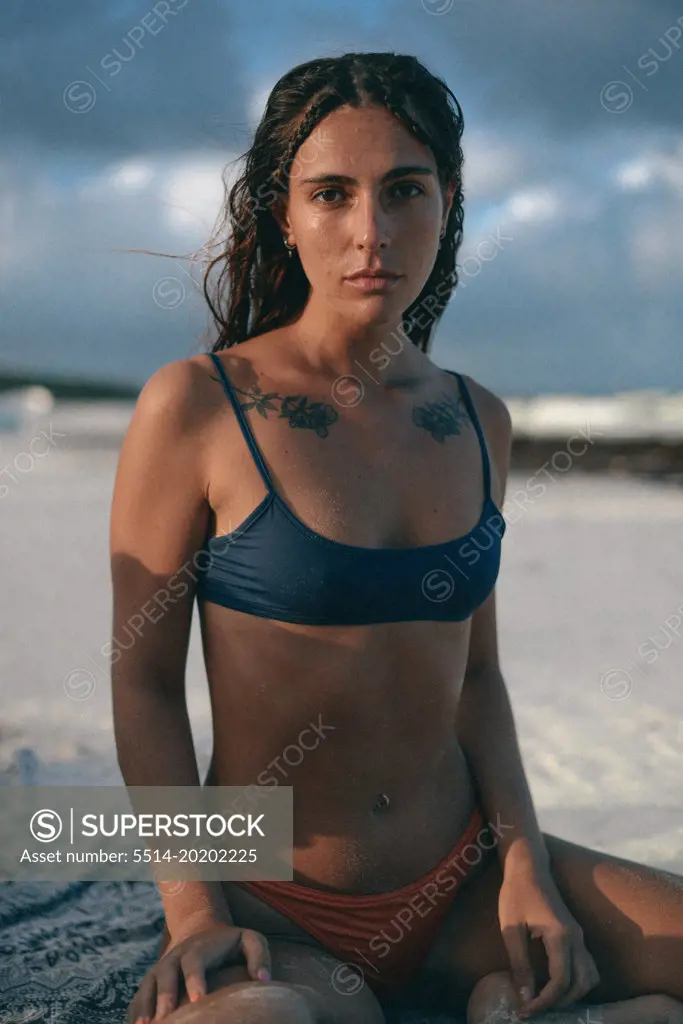 beauty girl with neck tattoos on the beach during the sunset