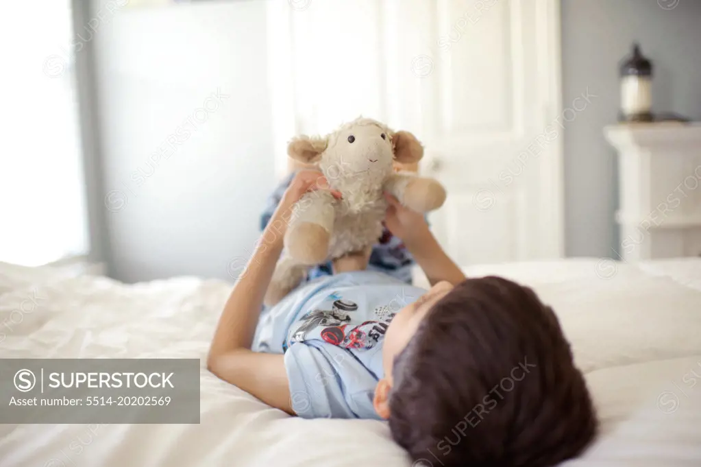 Boy Laying on Bed With Stuffed Animal