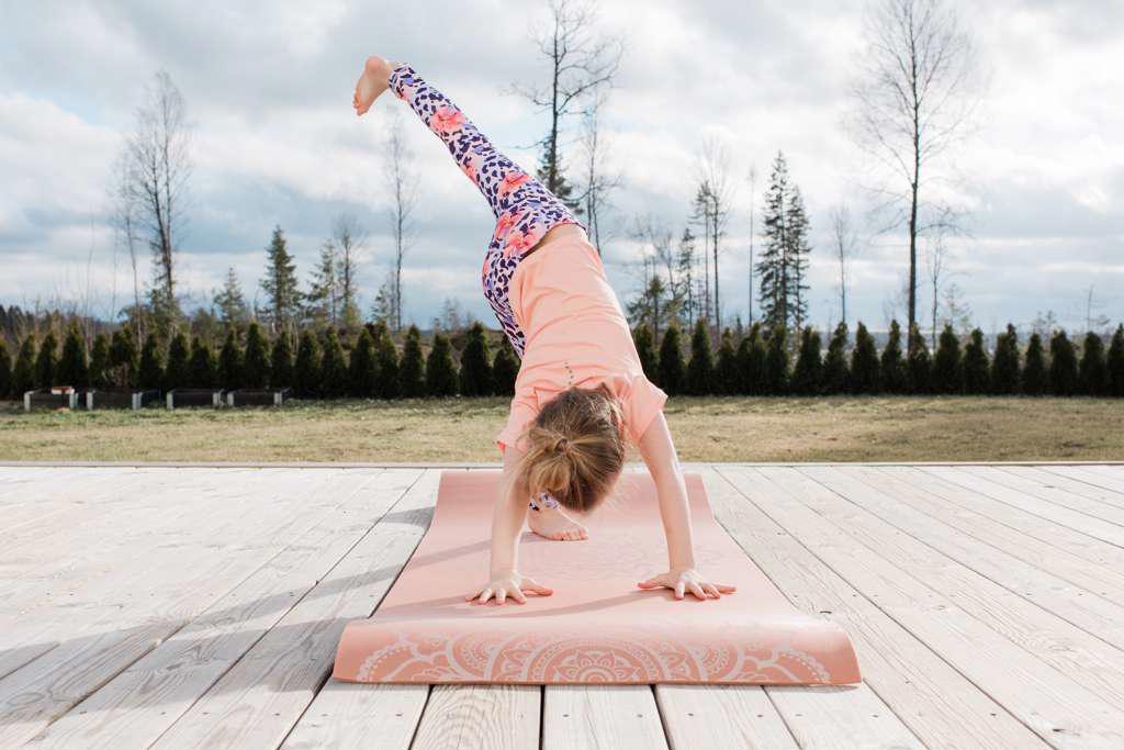 young girl stretching doing yoga in her back yard at home