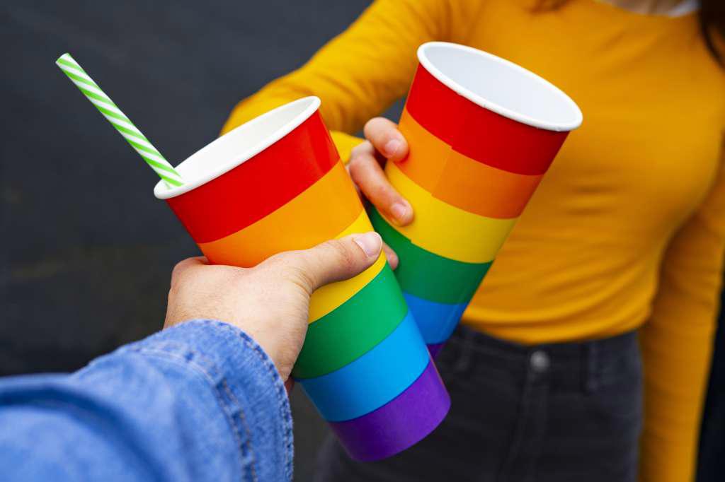 Hands toasting with rainbow pride cups at a party.