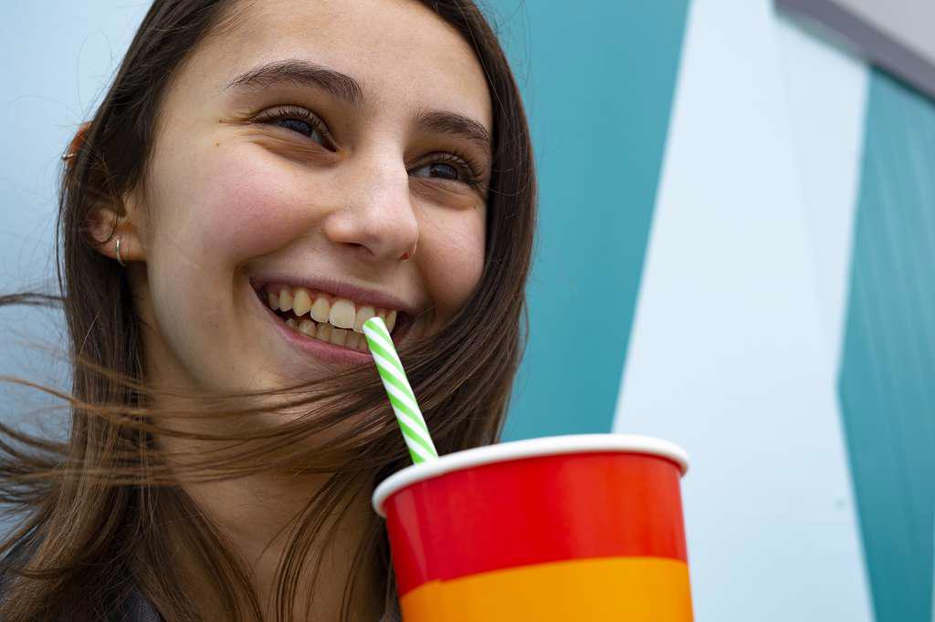 Woman smiling and drinking soda with a straw at a party.