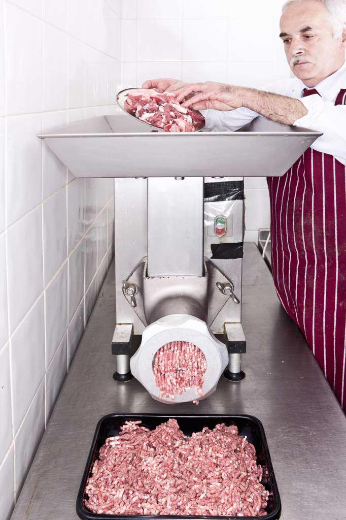 Butcher grinding meat in shop