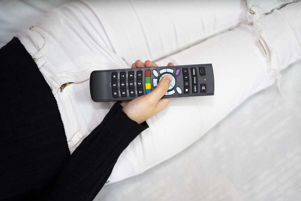 Woman using tv remote control in bed.