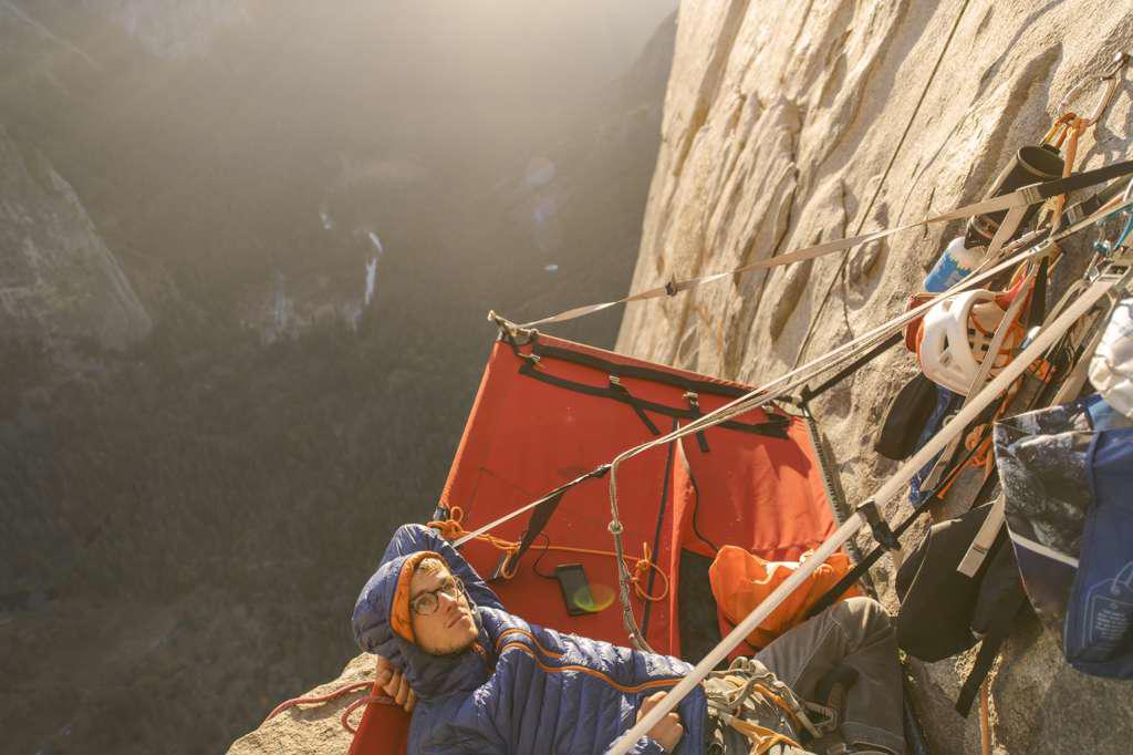 Climber laying on portaledge at sunset looking up at The Nose Capitan