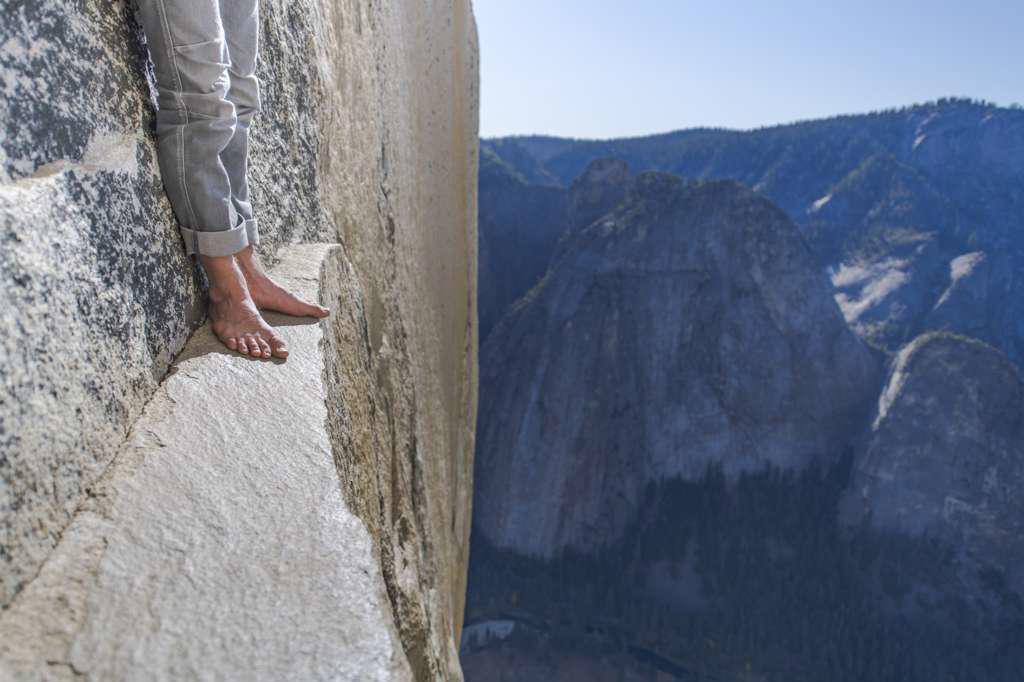 Man standing on a ledge, view of bare foot, very high El Capitan