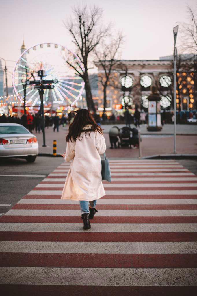 Rear view of young woman crossing road in city in winter