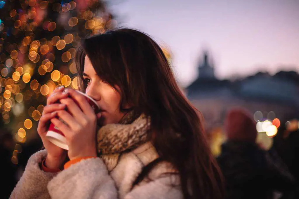 Portrait of teenage girl drinking mulled wine in Christmas market